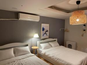 a bedroom with two beds and a lamp at WinSome_HongDae in Seoul