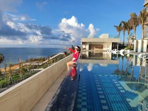 a woman standing on the edge of a swimming pool at APEC MANDALA CHAMBAY MŨI NÉ in Ấp Thiẹn Ái