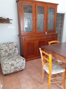 comedor con armario de madera, mesa y silla en Appartamento Riolunato (MO), en Riolunato