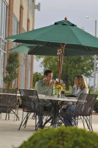 un hombre y una mujer sentados en una mesa bajo un paraguas en DoubleTree by Hilton Bay City - Riverfront, en Bay City