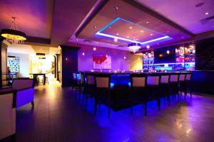 a bar in a restaurant with purple lighting at Hilton Garden Inn Olathe in Olathe