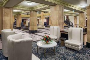 a lobby with chairs and a table with flowers on it at Hilton President Kansas City in Kansas City