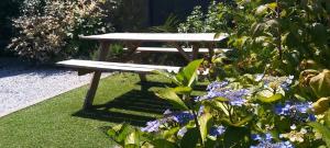 um banco de piquenique sentado num jardim com flores em Les hortensias de Stéfanick em Mûr-de-Bretagne