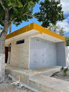 een bakstenen gebouw met een geel dak en een trap bij R Las chulas in Puerto Morelos