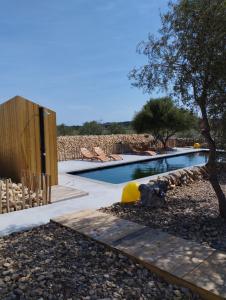 a swimming pool with a tree and some chairs at Mas des 4 Vents in Fitou