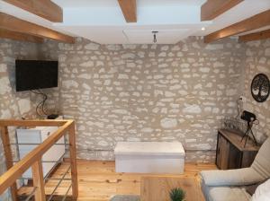 a living room with a stone wall with a tv at L'instant Civray in Civray-sur-Esves