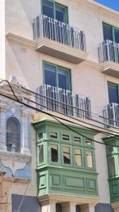 un edificio con puertas verdes y ventanas. en Privilege Suit SLiema, en Sliema