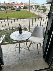 uma garrafa de vinho numa mesa e uma cadeira na varanda em Casa Leukos Salento - con terrazza privata em Vignacastrisi