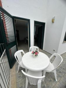 uma mesa branca com cadeiras brancas e um vaso de flores em Casa Leukos Salento - con terrazza privata em Vignacastrisi