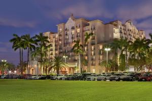 a large building with cars parked in a parking lot at Embassy Suites by Hilton Miami International Airport in Miami