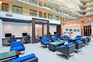 - une salle d'attente avec des tables et des chaises bleues dans l'établissement Embassy Suites by Hilton Miami International Airport, à Miami