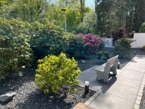 un jardín con un banco y algunos arbustos y flores en Ferienwohnung Poppelreiter, en Solingen