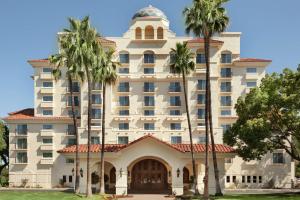 a large white building with palm trees in front of it at Embassy Suites by Hilton Milpitas Silicon Valley in Milpitas