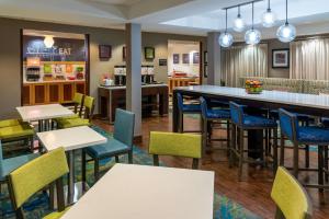 a restaurant with tables and chairs and a bar at Hampton Inn Kansas City-Lee's Summit in Lees Summit