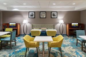 una sala de espera con mesas, sillas y TV en Hampton Inn Kansas City-Lee's Summit, en Lee's Summit