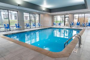 - une piscine avec des chaises bleues dans une chambre d'hôtel dans l'établissement Hampton Inn Kansas City-Lee's Summit, à Lee's Summit