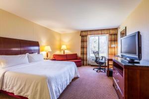 a hotel room with a bed and a flat screen tv at Hilton Garden Inn Milwaukee Northwest Conference Center in Milwaukee