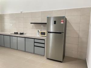 Una cocina con refrigerador de acero inoxidable y microondas. en Casa Forest Homestay, en Keluang