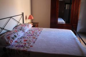 Una cama con un edredón blanco con flores. en LA CASA DEI POETI - C.I.R. 054039LOTUR19934, en Perugia