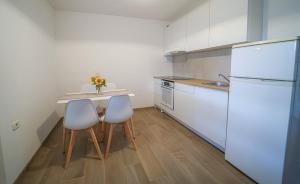 a kitchen with a table and two chairs and a refrigerator at Apartment Full Moon in Pobegi