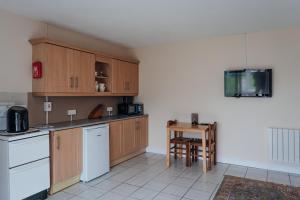 una cocina con armarios de madera y una mesa. en Ferry Lodge Cottage, en Kilrush