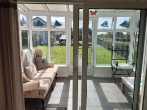 a living room with a couch in front of windows at Ferry Lodge Cottage in Kilrush