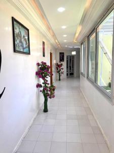 een hal met twee vazen bloemen aan de muur bij Hôtel Ami Bamba in Mbour