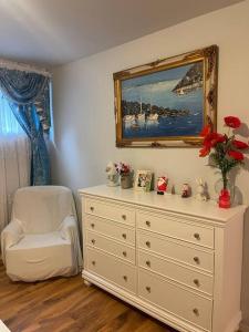 a white dresser with a white chair and a mirror at Four Seasons Private Villa in Powell River