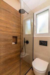 a bathroom with a toilet and a glass shower at KŌRES Your Tinos Summer Retreat in Agios Ioannis Tinos