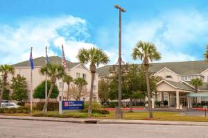 a large building with palm trees in front of it at Hilton Garden Inn New Orleans Airport in Kenner