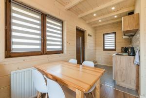 a dining room with a wooden table and white chairs at Domki Bieszczadzkie Marzenie 781-966-947 in Polańczyk