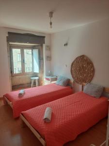 a bedroom with two beds with red sheets and a window at Benedita's House in Capinha