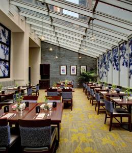 uma sala de jantar com mesas e cadeiras de madeira e janelas em Hilton Garden Inn New York/Manhattan-Chelsea em Nova York