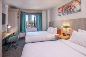 a hotel room with two beds and a desk and a window at Hilton Garden Inn New York/Manhattan-Chelsea in New York