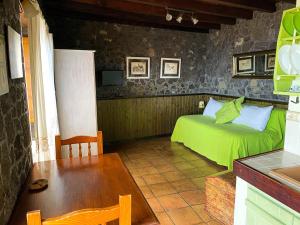 Un dormitorio con una cama verde y una mesa en Estudio Rural de Piedra en Frontera