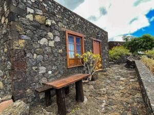 a wooden bench sitting outside of a stone building at Estudio Rural de Piedra in Frontera +10 photos