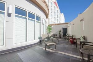 un patio al aire libre con mesas, sillas y ventanas en Hilton Garden Inn Oklahoma City Midtown, en Oklahoma City