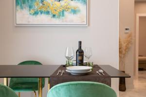 a dining room table with a bottle of wine and green chairs at Ginex Luxury Suite in Trani