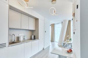 a kitchen with white cabinets and a table at Wave Prestige Studio - Sea View - SPA&Pools in Międzyzdroje