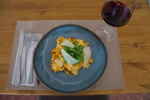 eine blaue Platte Essen auf einem Tisch mit einem Glas Wein in der Unterkunft Casa M Vineyard in Chianciano Terme