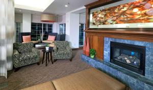 Hilton Garden Inn Ontario Rancho Cucamonga في رانشو كوكامونجا: غرفة معيشة مع موقد وتلفزيون