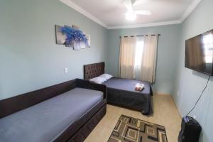 uma sala de estar com duas camas e uma televisão em Até 8 Hóspedes, Linda Vista, Piscina, Salão de Jogos e Brinquedoteca em Ouro Preto
