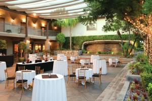 a restaurant with white tables and chairs in a courtyard at DoubleTree by Hilton Claremont in Claremont