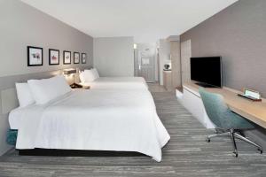 a hotel room with two beds and a desk and a television at Hilton Garden Inn Evanston in Evanston