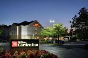 uma placa de hotel com jardim em frente a um edifício em Hilton Garden Inn Newport News em Newport News