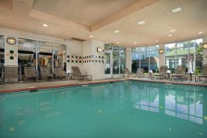 a swimming pool in a hotel with chairs and tables at Hilton Garden Inn Newport News in Newport News