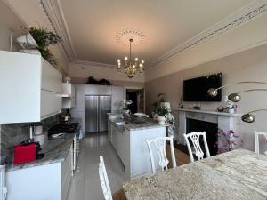 a kitchen with white cabinets and a table and chairs at Stunning West End 3 Bed in Glasgow