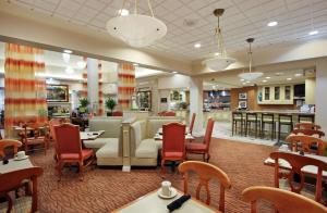 Hilton Garden Inn Chesapeake Greenbrier في تشيسابيك: مطعم بطاولات وكراسي وبار