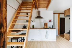 uma cozinha com armários brancos e uma escada de madeira em Apartman 19 em Banská Štiavnica