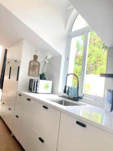 a white kitchen with a sink and a window at Penthouse Furnas in Furnas